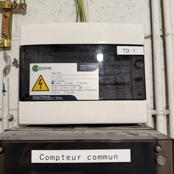 Tableau électrique des communs de la copropriété ACP Dîme avec l'étiquette de réception Apave, mise en conformité RGIE par Debelec