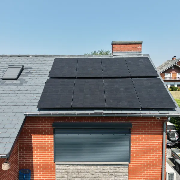 Les panneaux solaires dominent la façade en brique et la cheminée