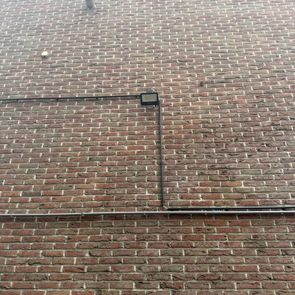 Conduits et boîtes de dérivation en finition noire intégrés au mur en brique
